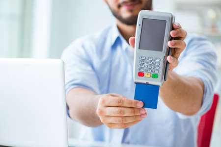 Man processing credit card transaction with POS terminalの写真素材