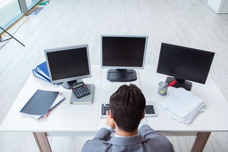 Businessman sitting in front of many screensの写真素材