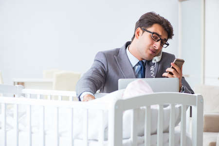 Young businessman trying to work from home caring after newborn babyの写真素材