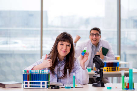 Two chemists working in lab experimentingの写真素材