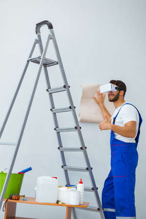 Man with VR glasses gluing wallpaperの写真素材
