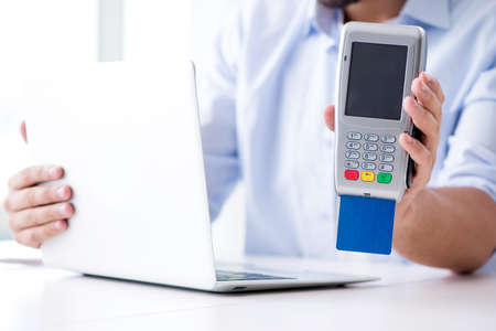 Man processing credit card transaction with POS terminalの写真素材