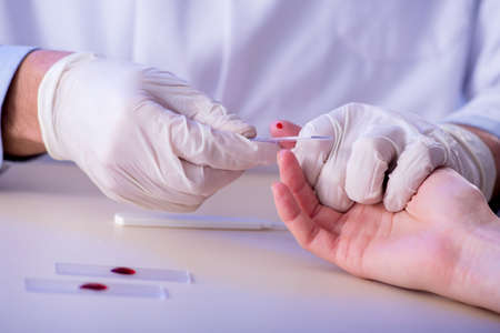 Doctor taking blood samples from fingerの写真素材