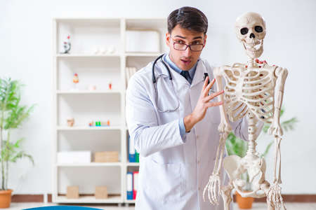 Yong male doctor with skeleton isolated on whiteの写真素材