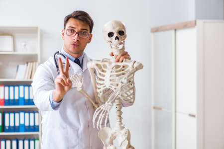 Yong male doctor with skeleton isolated on whiteの写真素材