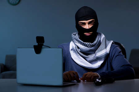Hacker wearing balaclava mask hacking computerの写真素材