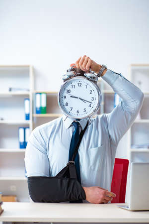 Businessman with broken arm working in officeの写真素材