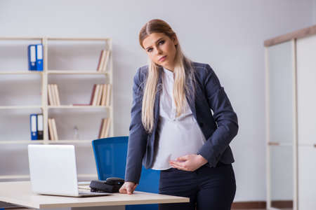 Pregnant woman employee in the officeの写真素材
