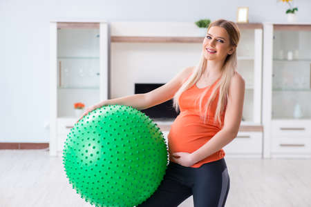 Young woman preparing for birth exercising at homeの写真素材