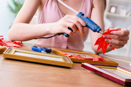 Woman decorating picture frame in scrapbooking conceptの写真素材