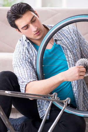 Young man repairing bicycle at homeの写真素材