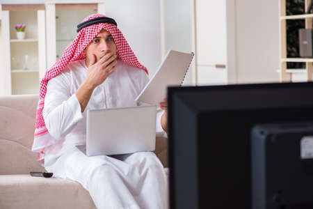 Arab businessman watching tv at homeの写真素材