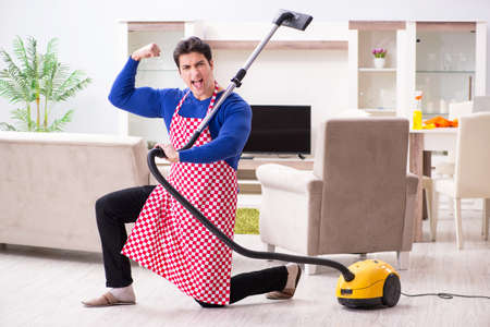 Young man vacuum cleaning his apartmentの写真素材