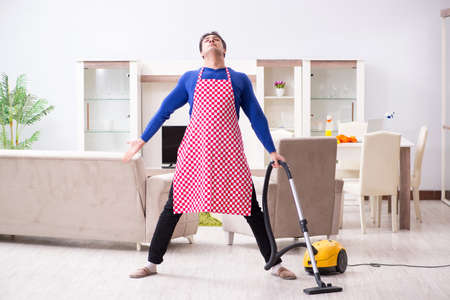 Young man vacuum cleaning his apartmentの写真素材