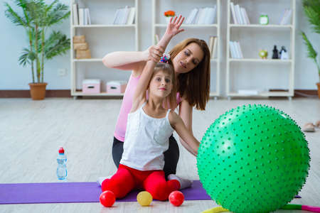 Girl and mother exercising at homeの写真素材