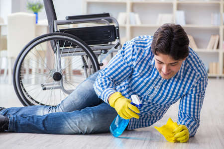 Disabled man on wheelchair cleaning homeの写真素材