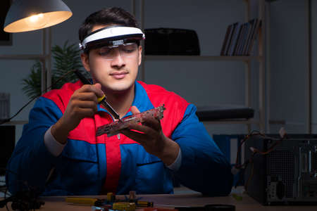 Computer specialist repairing PC late at night