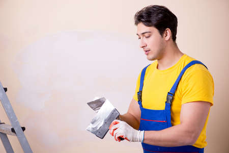 Young contractor employee applying plaster on wallの写真素材