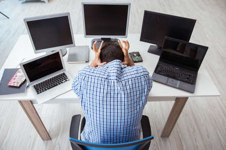 Businessman sitting in front of many screens