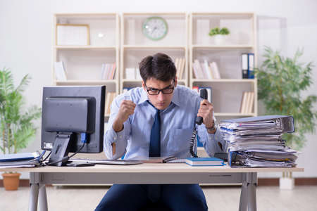 Angry businessman frustrated with too much workの写真素材