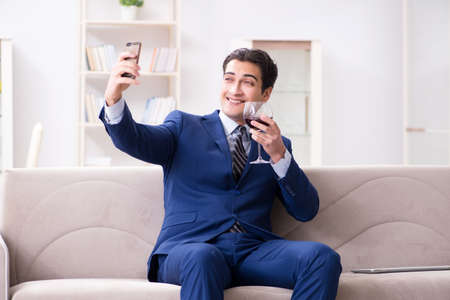 Businessman drinking wine sitting at homeの写真素材