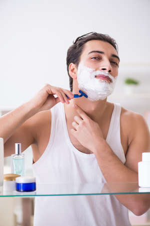 Young handsome man shaving early in the morning at homeの写真素材
