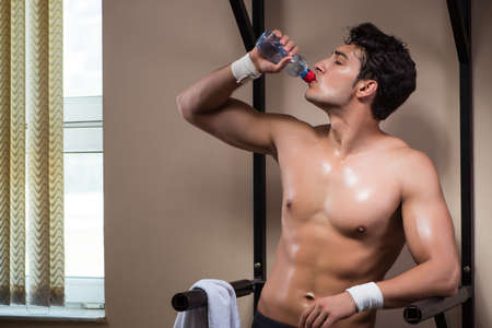 Thirsty man drinking water in sports gym