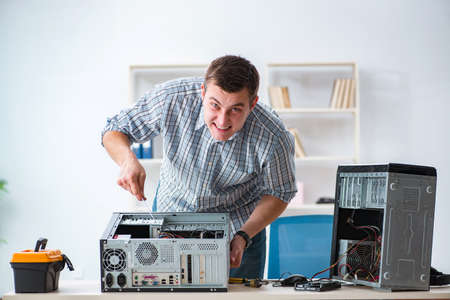 Young technician repairing computer in workshopの写真素材