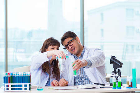 Two chemists working in lab experimentingの写真素材