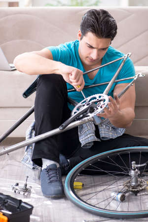 Young man repairing bicycle at homeの写真素材