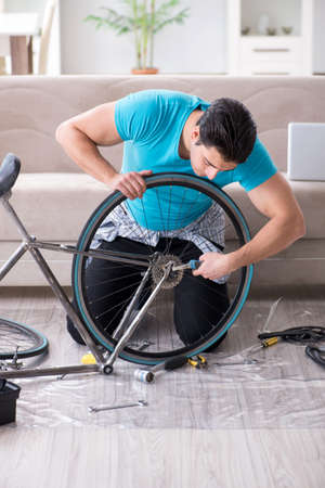 Young man repairing bicycle at homeの写真素材