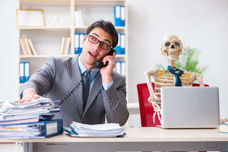 Businessman working with skeleton in officeの写真素材