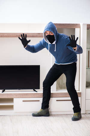 Man burglar stealing tv set from houseの写真素材