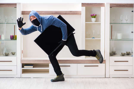Man burglar stealing tv set from houseの写真素材