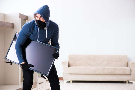 Man burglar stealing tv set from houseの写真素材