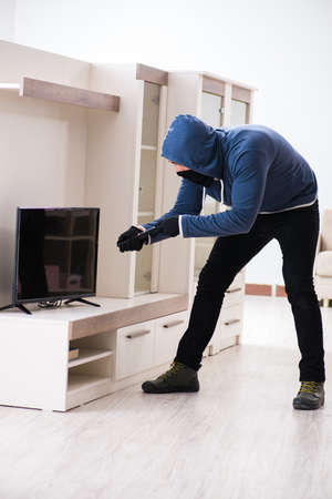 Man burglar stealing tv set from houseの写真素材
