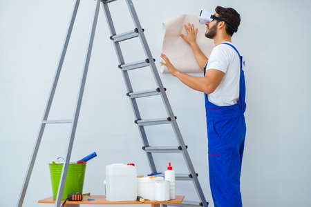 Man with VR glasses gluing wallpaperの写真素材