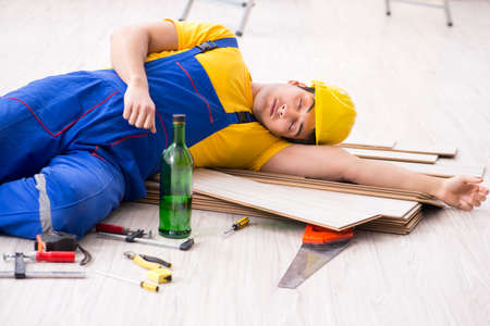 Floor repairman drinking alcohol during breakの写真素材