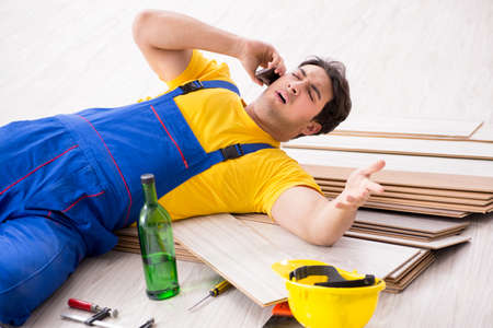 Floor repairman drinking alcohol during breakの写真素材