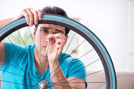 Young man repairing bicycle at homeの写真素材