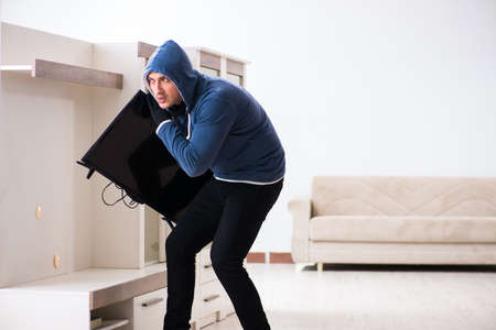 Man burglar stealing tv set from house