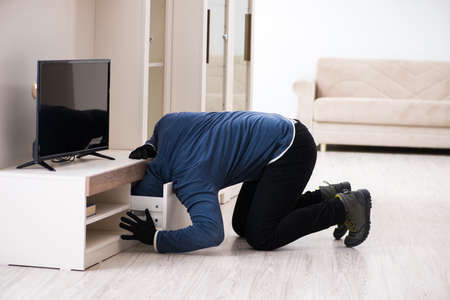 Man burglar stealing tv set from houseの写真素材