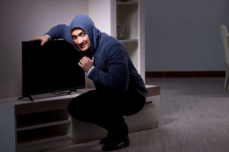 Burglar thief stealing tv from apartment houseの写真素材