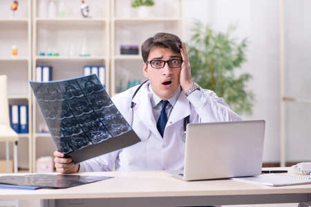 Young doctor looking at x-ray images in clinicの写真素材
