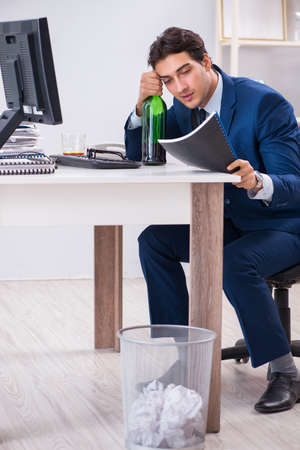 Young businessman employee drinking in the office at deskの写真素材