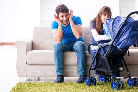 Young parents with their newborn baby in baby pram sitting on thの写真素材