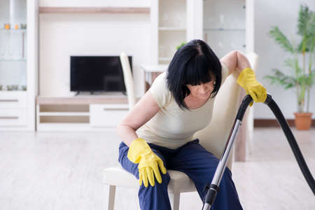 Senior old woman tired after vacuum cleaning houseの写真素材