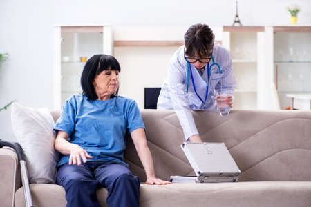 Young doctor visiting old mature woman for check-upの写真素材