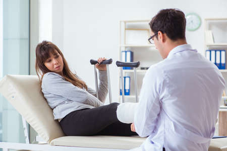 Doctor examining patient with broken leg