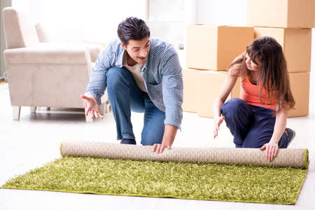 Young family rolling carpet at new apartmentの写真素材